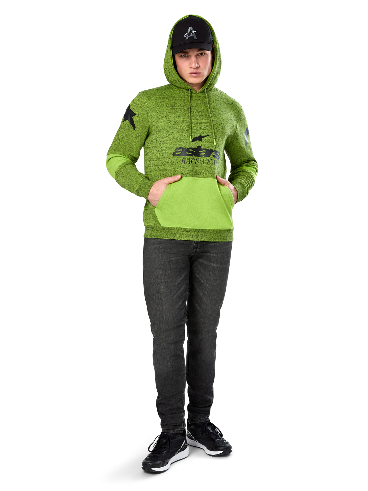 Sweat à capuche Perpetuate Alpinestars, molleton chiné vert lime avec poche kangourou et empiècements aux manches vert vif contrastants, graphisme 'astars' noir sur le devant, porté avec une casquette noire et un jean foncé, streetwear décontracté inspiré du sport automobile