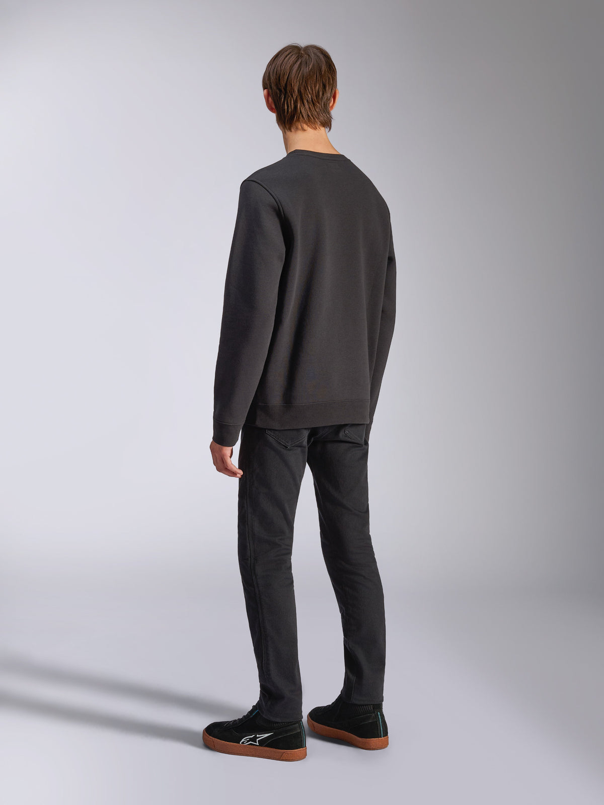 Alpinestars Positive Crew, zwarte pullover sweatshirt, achteraanzicht op model, casual motorsport-geïnspireerde streetwear, voorzien van een geribbelde zoom en manchetten.