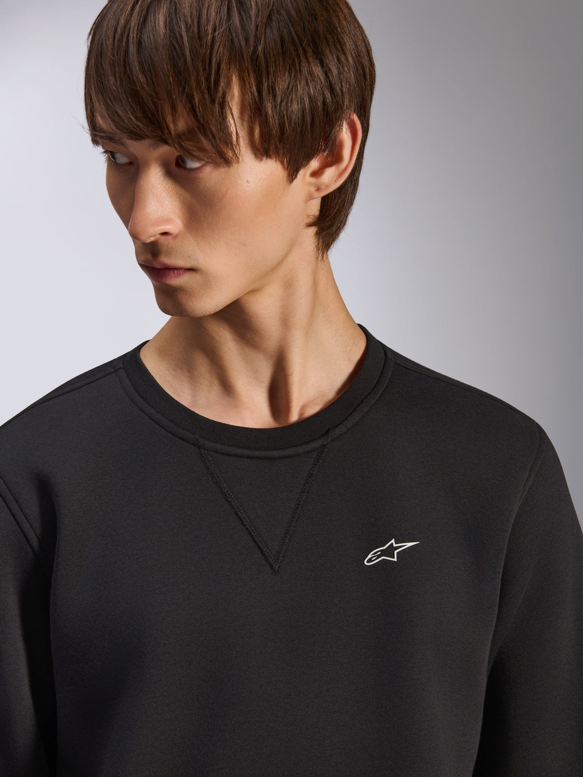 Alpinestars Positive Crew sweatshirt, zwarte crewneck met V-stiksel detail bij de hals, klein wit Alpinestars-logo op de linkerborst, casual op motorsport geïnspireerde streetwear