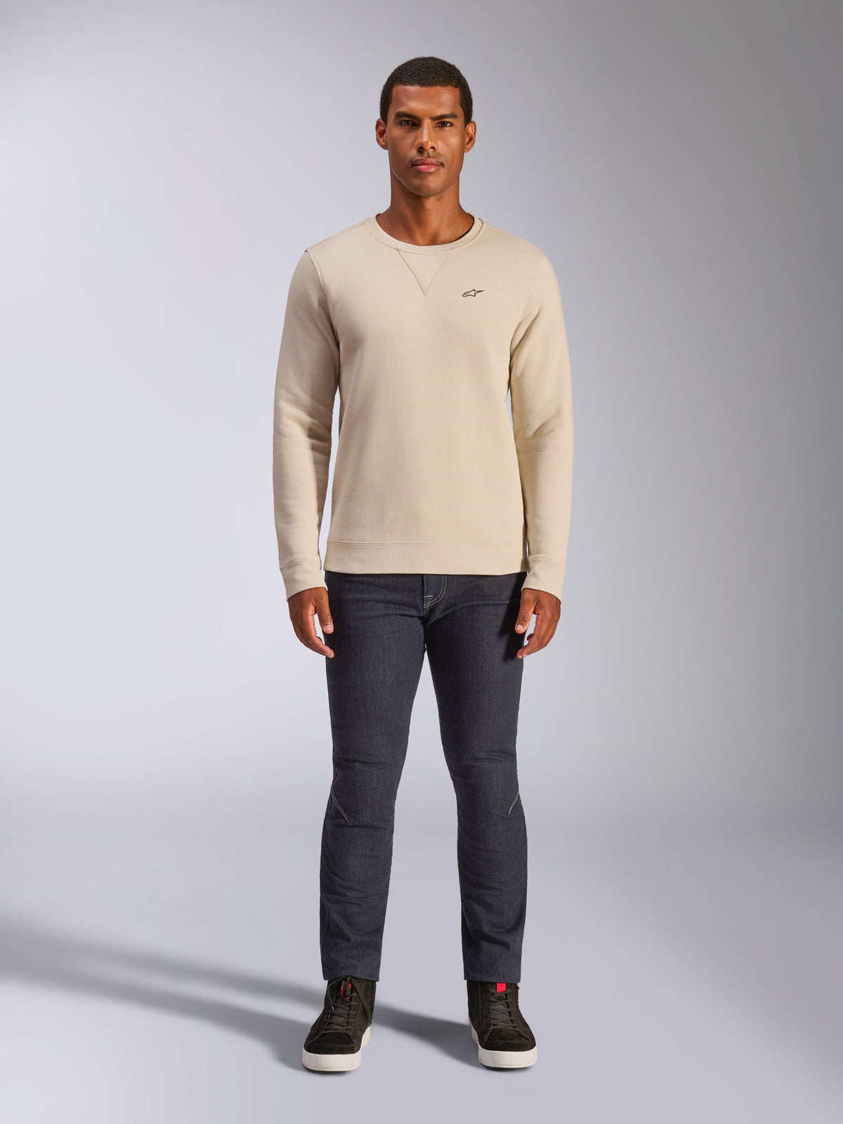 Alpinestars Positive Crew, Off White sweatshirt met ronde hals, klein zwart logo op de borst, geribbelde manchetten en zoom, driehoekig stiksel bij de hals, casual motorsport streetwear gedragen met een donkere jeans