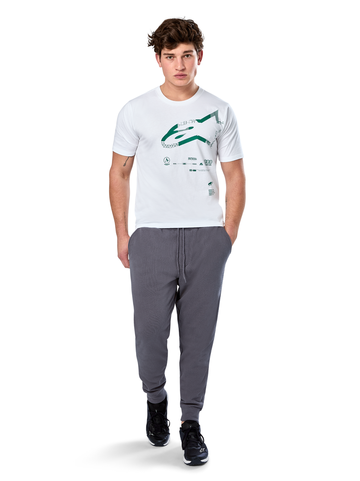 Alpinestars Geografica CSF Tee, Kurzarm-T-Shirt, Weiß, grünes Astars-Logo mit geografischer Multi-Tech-Grafik, getragen mit grauer Jogginghose und schwarzen Sneakern, lässige Motorsport-Streetwear