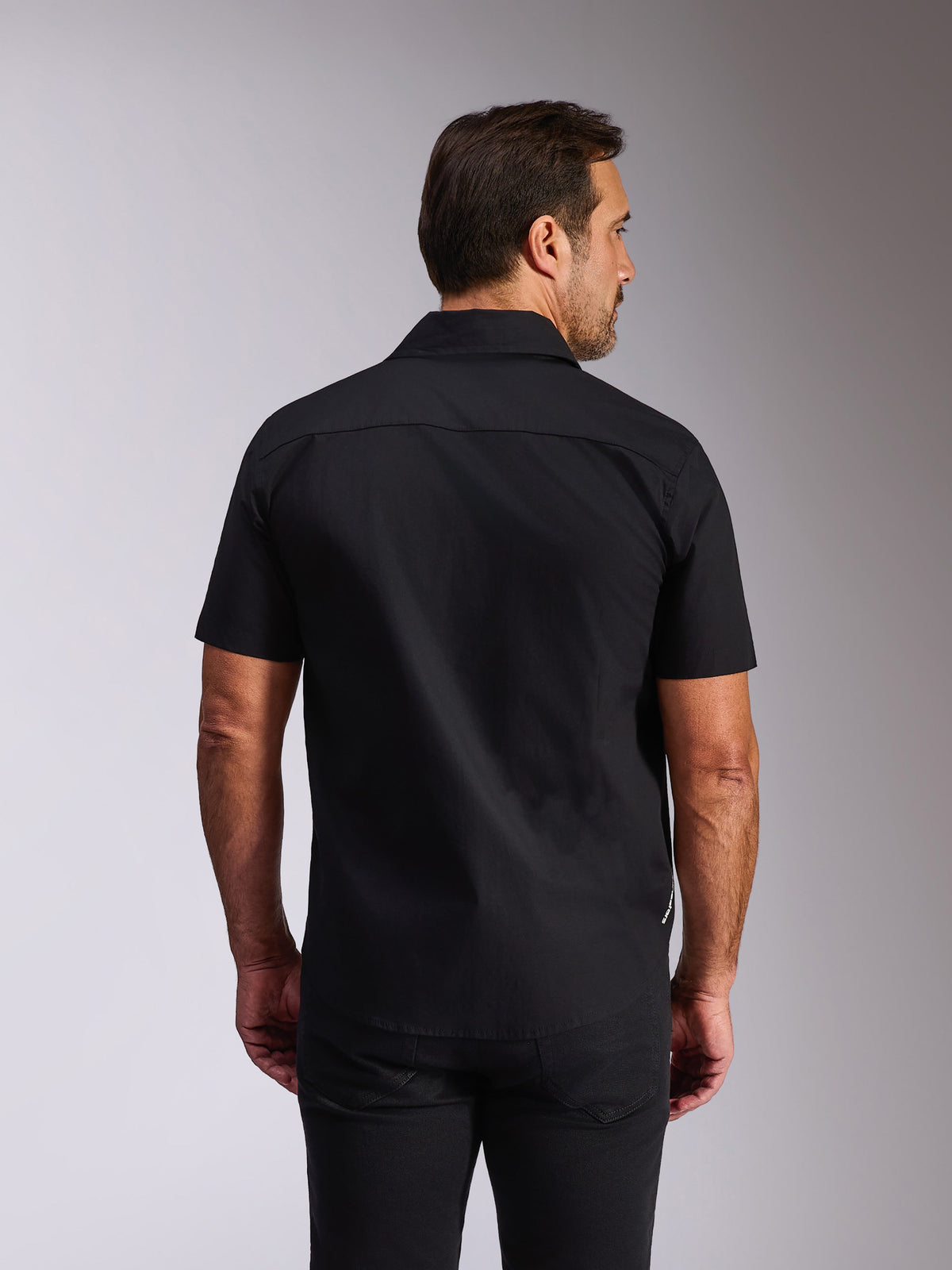 Alpinestars Strive Woven Hemd, schwarzes Kurzarmhemd mit Knopfleiste, Rückansicht zeigt Rückenpasse und taillierte Passform, lässige vom Motorsport inspirierte Streetwear