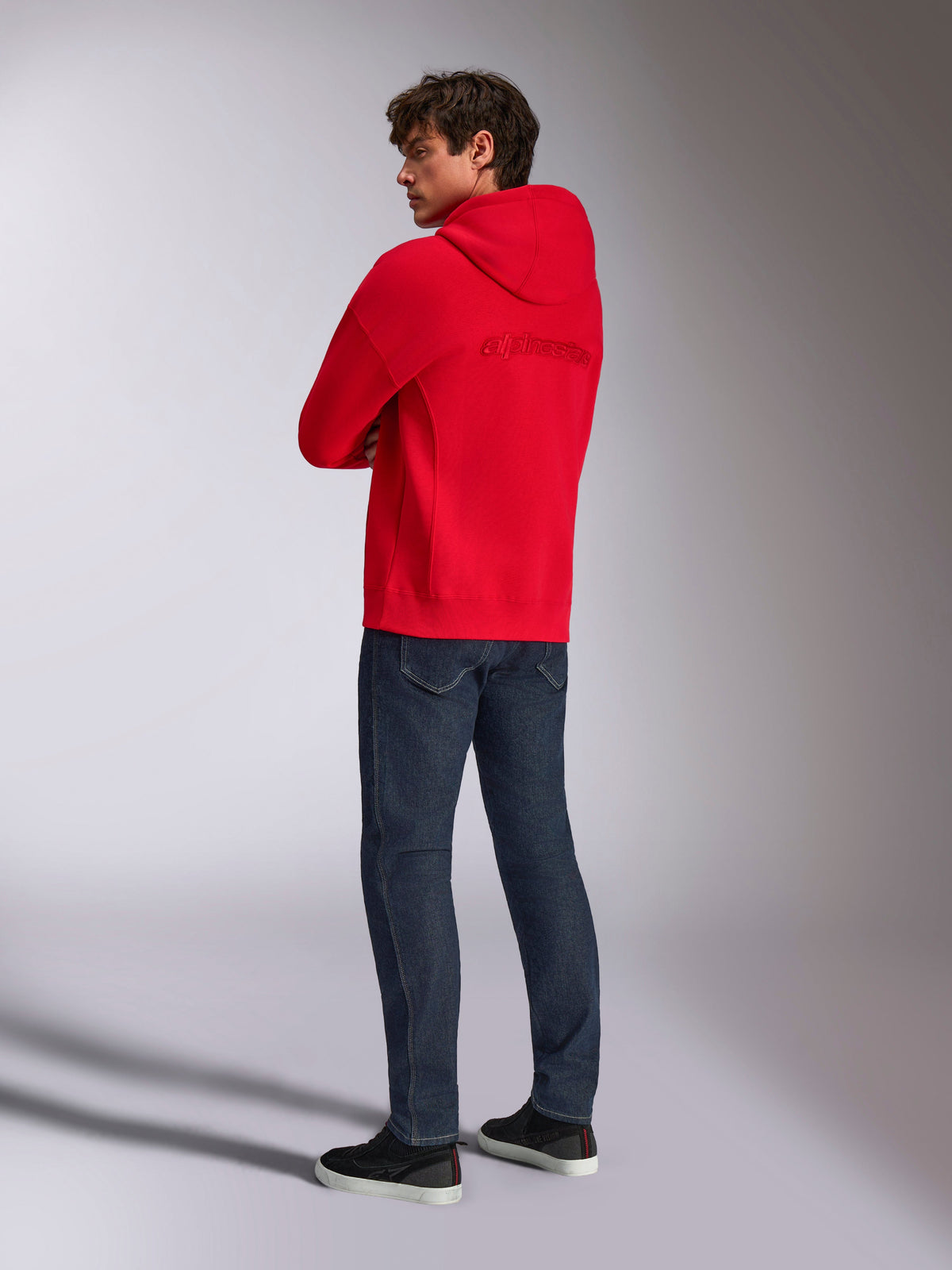 Alpinestars Emergent Oversized Hoodie, Rot, Rückansicht mit besticktem Alpinestars-Wortlogo auf dem Rücken, Oversized-Passform, getragen mit dunkelblauer Jeans und schwarzen Sneakern, lässige Lifestyle-Streetwear
