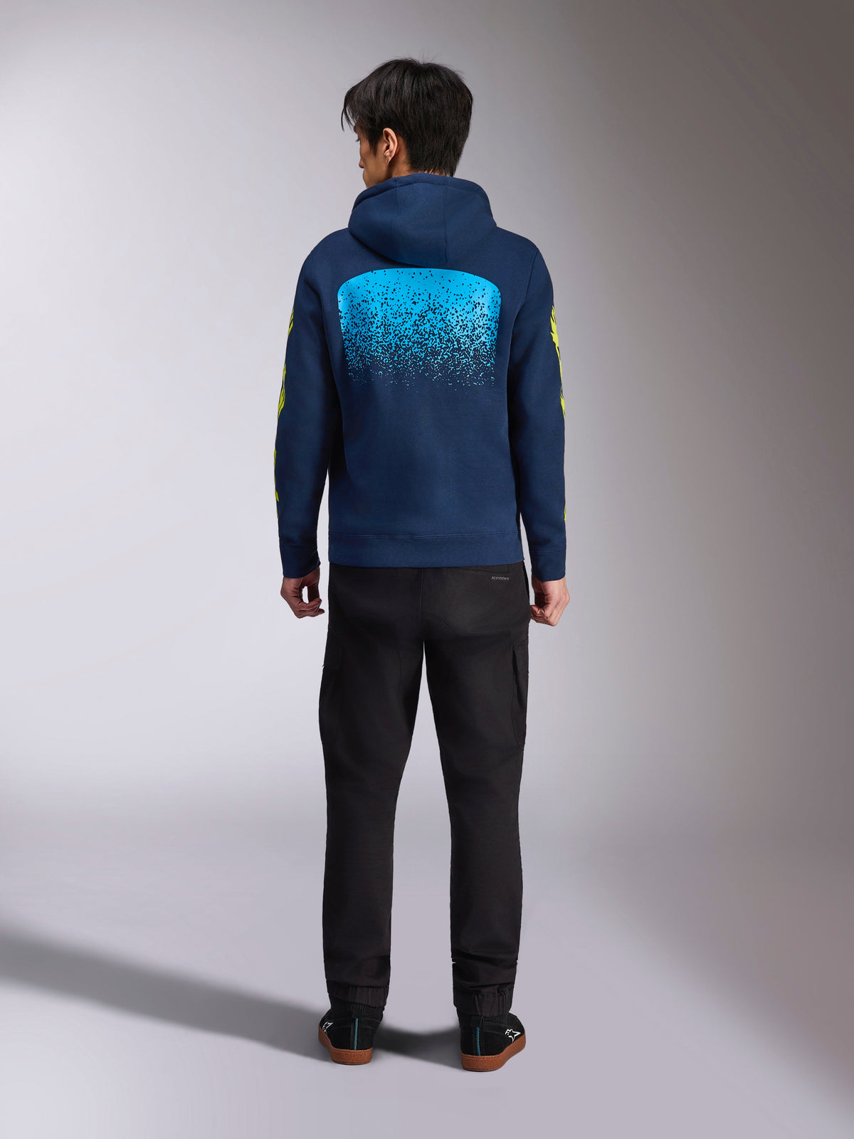 Alpinestars Obsessed Hoodie in Navy-Blau, Rückansicht mit großer cyanfarbener MX-Farbverlauf-Grafik und gelben Ärmel-Logos, lässiger Motorsport-Pullover aus Fleece.