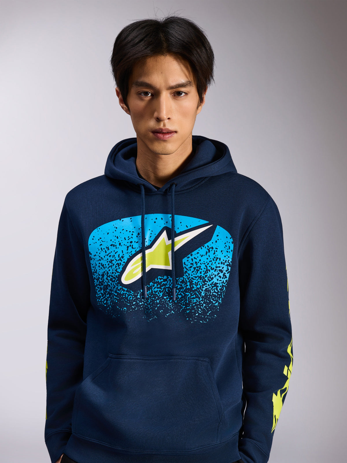 Alpinestars Obsessed Kapuzenpullover, marineblauer Fleece-Hoodie, Astars-Logo auf der Vorderseite mit blauem MX-Farbverlauf und lindgrünen Akzenten, gelbe Wortmarken-Logos auf den Ärmeln, lässige vom Motorsport inspirierte Streetwear