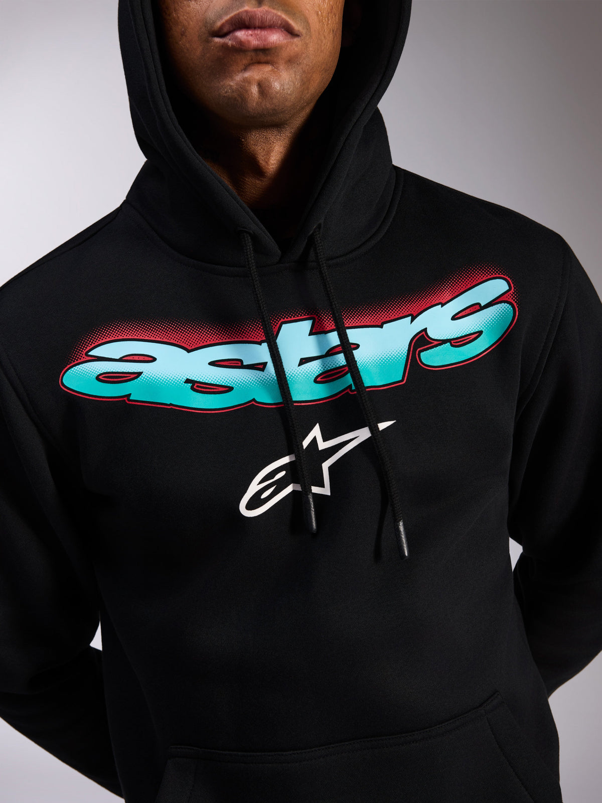 Alpinestars Ellipsoid Hoodie, schwarzer Fleece-Kapuzenpullover, Astars-Schriftzug mit blau-türkisem Farbverlauf und roten Halbtoneffekten, weißes Stern-Logo, Kapuze mit Kordelzug, lässige, vom Motorsport inspirierte Streetwear