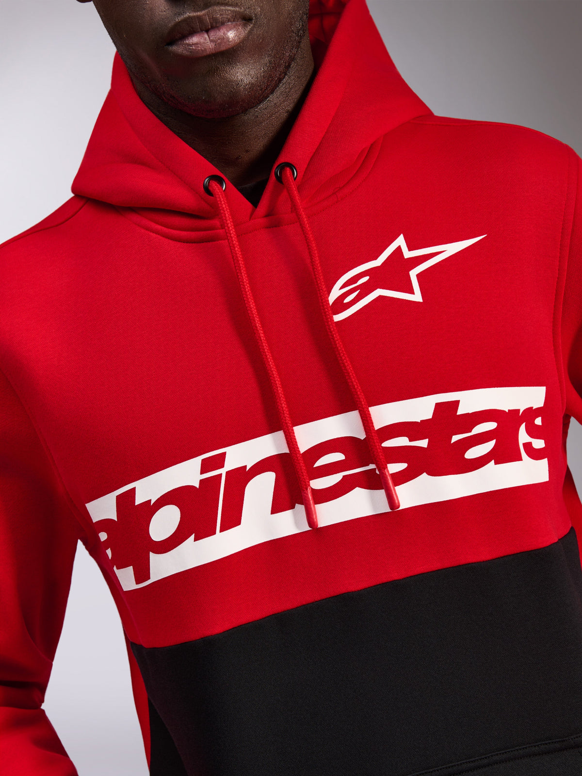 Alpinestars Parallel Hoodie, rood en zwart kleurgeblokkeerd fleece, met een wit Astars-logo en rood Alpinestars-woordmerk op een witte borstband, capuchon met trekkoord, casual motorsport-geïnspireerde streetwear