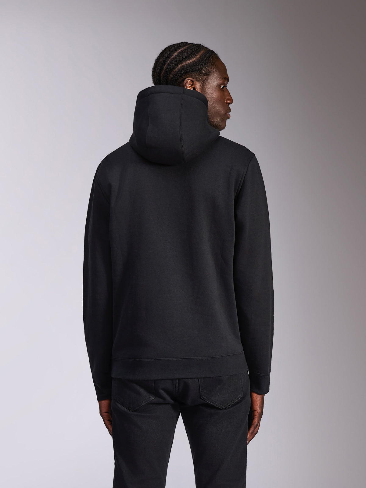Alpinestars Pulse Hoodie, zwart, achteraanzicht op model, casual streetwear, pullover fleece met capuchon en effen zwart ontwerp, geribde manchetten en zoom, gecombineerd met een zwarte broek