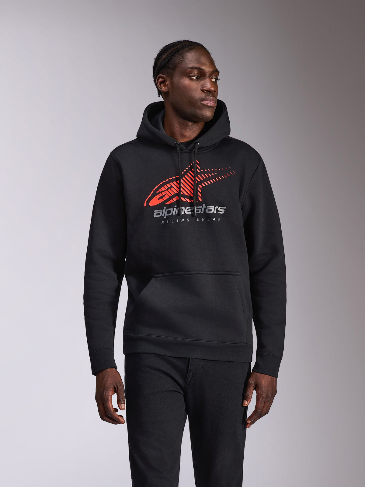 Alpinestars Pulse Hoodie, casual pullover hoodie, zwart met rood en grijs Astars-logo voorzien van speed line fade en 'Racing Ahead'-tekst, capuchon met trekkoord en kangoeroezak, motorsport-geïnspireerde streetwear gedragen door een model