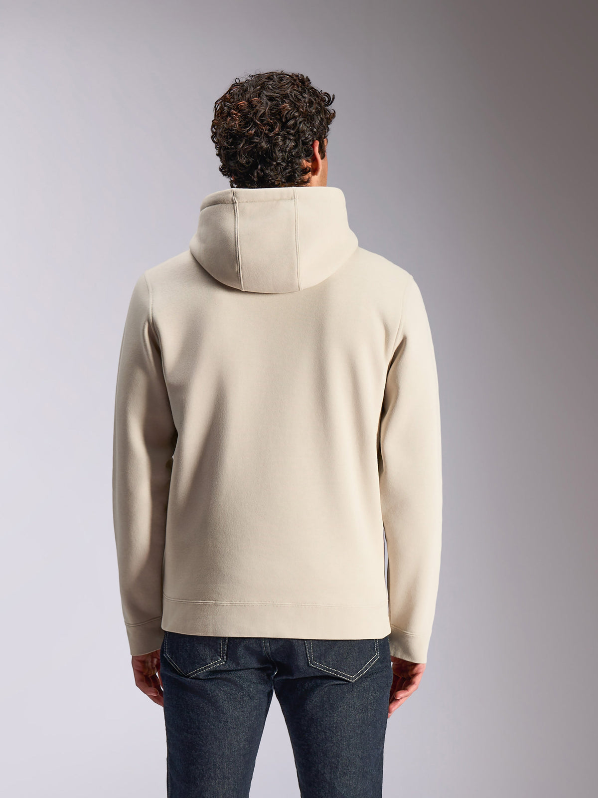 Sweat à capuche Alpinestars Pulse, couleur sable, vue de dos d'un mannequin homme portant le sweat à capuche uni, associé à un jean en denim foncé, streetwear décontracté d'inspiration sport mécanique
