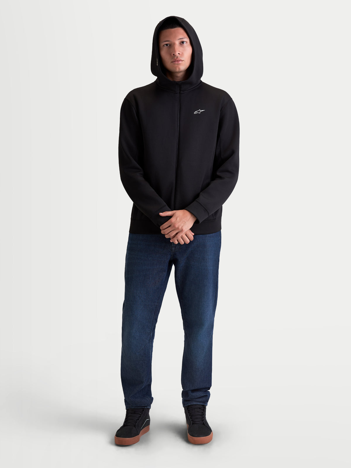 Alpinestars Cypher Kapuzenpullover, Sportswear Full-Zip-Hoodie, Herren, Schwarz, Tri-Blend-Doppelvlies mit hohem Kragen und Mesh-gefütterter Kapuze, kleines weißes Astars-Logo auf der Brust, getragen von einem Modell für den Alltag.