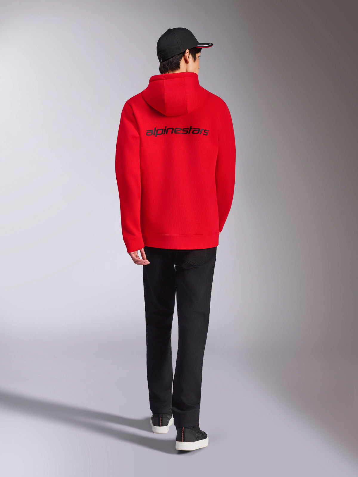 Alpinestars Transverse Hoodie, Rote lässige Streetwear, Rückansicht mit schwarzem Alpinestars-Wortlogo, Kapuzenfleecejacke, kombiniert mit schwarzer Kappe und schwarzer Hose