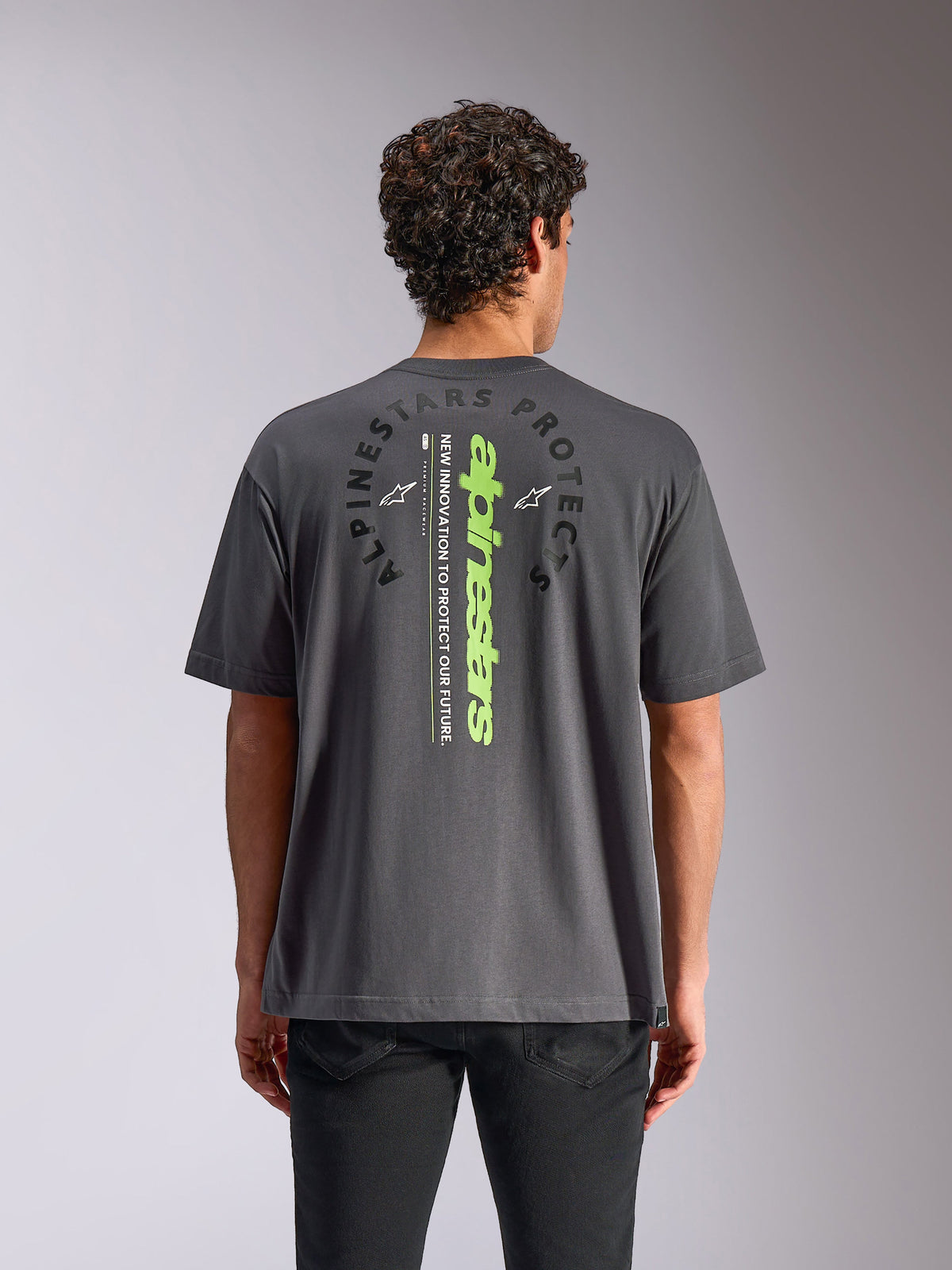 Alpinestars Overhang Oversized CSF Tee, T-shirt met korte mouwen, antracietgrijs, achteraanzicht met verticaal neongroen woordmerk en cirkelvormige grafiek, relaxte oversized pasvorm, casual motorsport streetwear