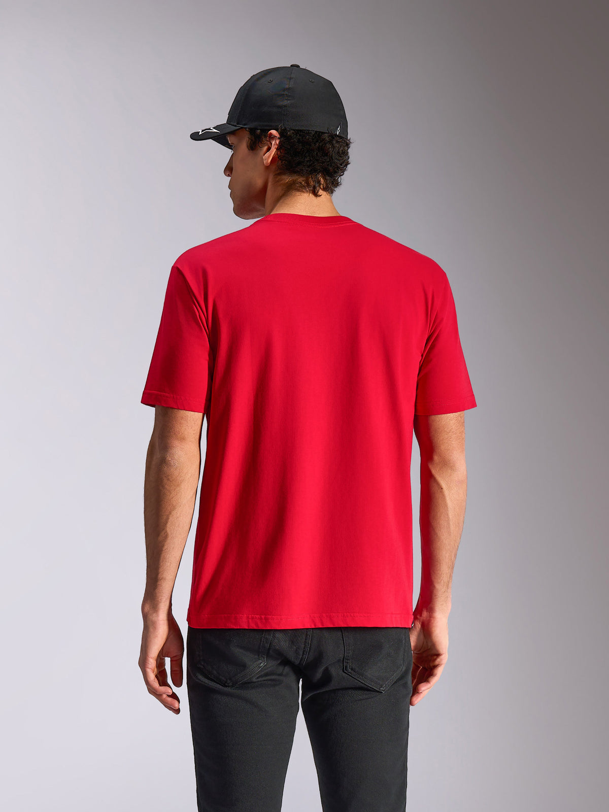 Alpinestars Noka CSF Tee, T-shirt met korte mouwen, rood, achteraanzicht op model, casual motorsport streetwear, gestyled met zwarte pet en donkere broek