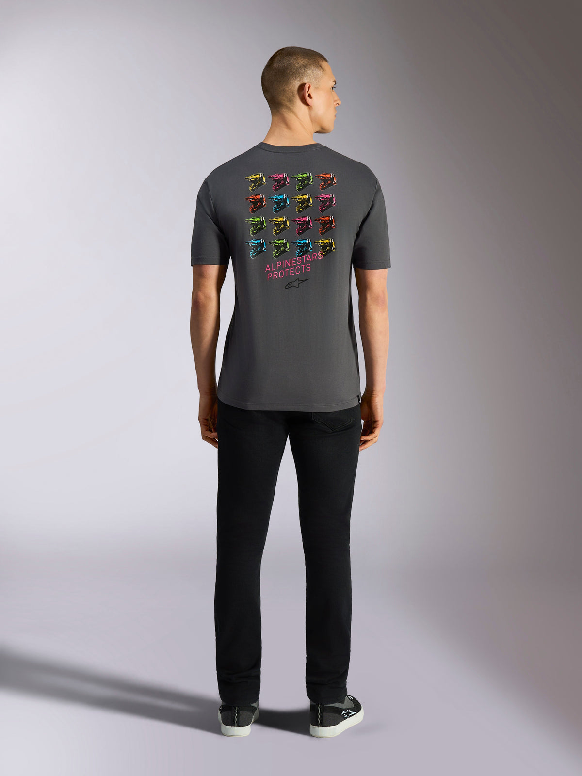 Alpinestars Pop Helmet CSF Tee, t-shirt met korte mouwen, houtskoolgrijs, met een raster van veelkleurige M10-helmafbeeldingen op de achterkant en de tekst 'ALPINESTARS PROTECTS', casual motorsport streetwear