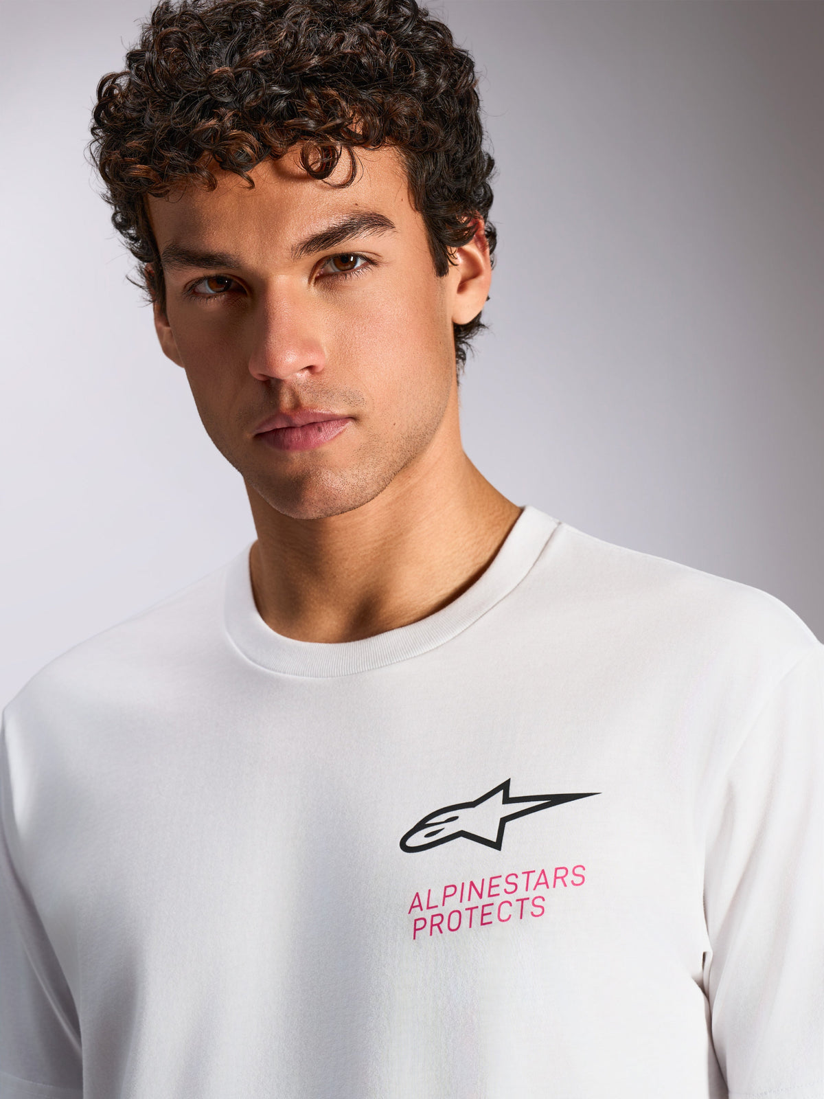 T-shirt Alpinestars Pop Helmet CSF, t-shirt à manches courtes, blanc, logo Astars noir et texte 'ALPINESTARS PROTECTS' rose sur la poitrine, streetwear décontracté inspiré du sport automobile