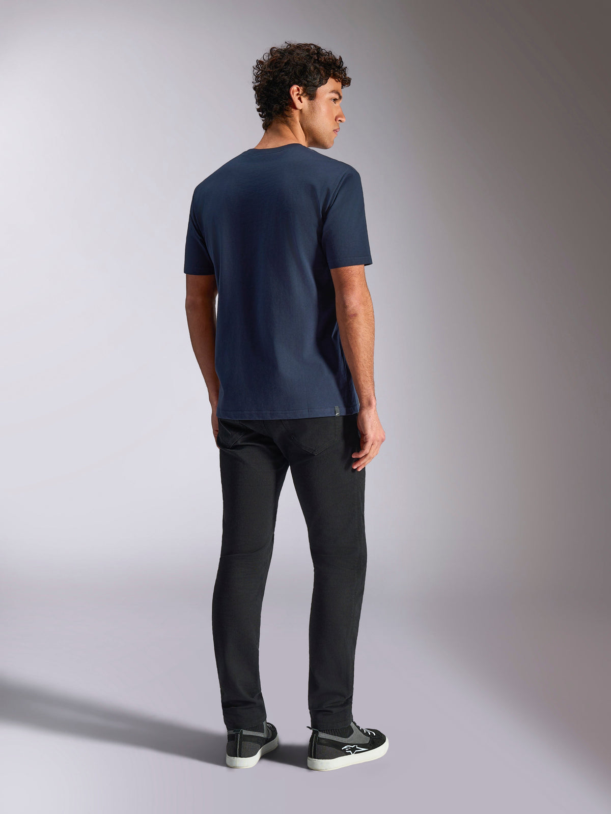 Alpinestars Trifecta CSF Tee, Kurzarm-T-Shirt, Marineblau, Rückansicht, lässige Sportbekleidung, getragen mit schwarzer Hose und schwarzen Sneakern