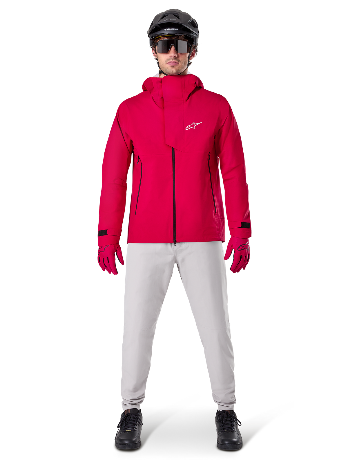 Veste imperméable Alpinestars A-Dura Elite, rouge fluo, veste technique de VTT portée avec un casque de VTT noir, des lunettes de soleil, des gants rouges assortis et un pantalon gris clair, vue d'ensemble de l'équipement de cyclisme toutes saisons