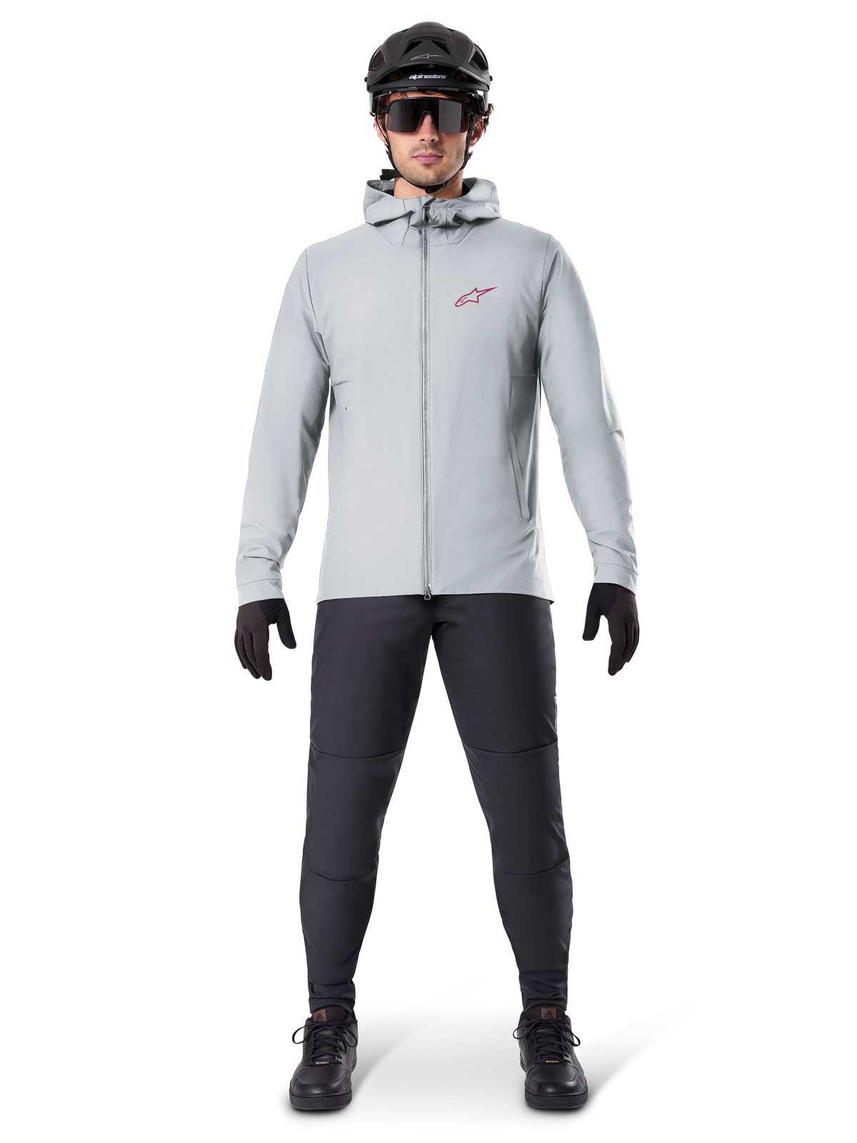 Veste thermique Alpinestars A-Dura, gris titane, veste de cyclisme portée avec un pantalon de VTT noir, des gants et un casque, dotée d'un petit logo étoile rouge sur la poitrine et d'une fermeture éclair frontale intégrale, équipement isolant léger pour le tout-terrain.