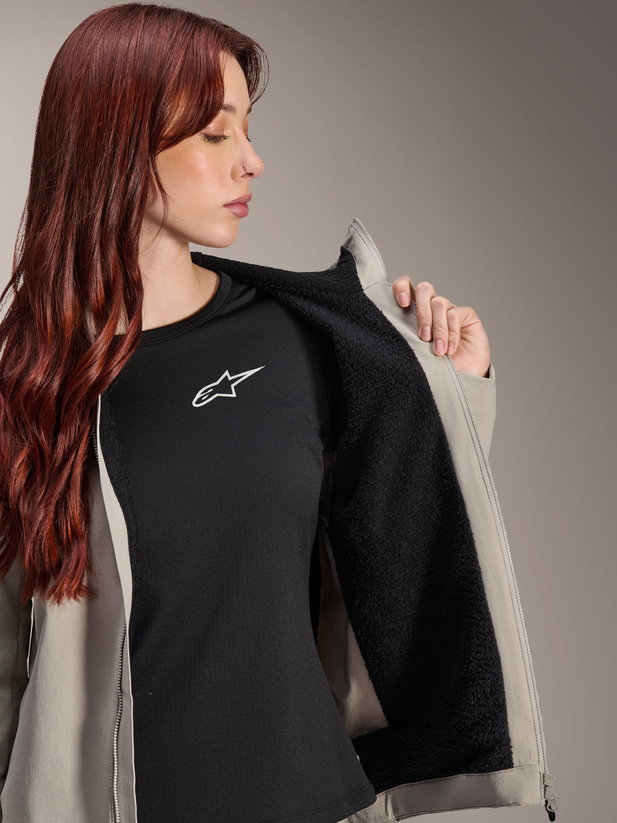 Alpinestars Stella A-Dura Thermal Jacket in Titanium, vrouw draagt de jas en toont de zwarte getextureerde fleece voering, gedragen over een zwart t-shirt met wit sterlogo, lichtgewicht mountainbikejas voor koude omstandigheden