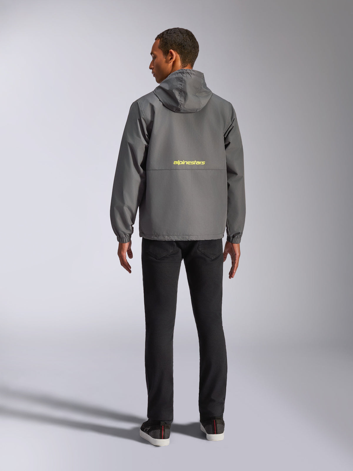 Alpinestars Speeder Chromium Windbreaker-Jacke, Charcoal und Hi-Vis Gelb, Rückansicht mit gelbem Alpinestars-Logo in der Mitte, leichter Windbreaker mit Kapuze und elastischen Bündchen, lässige, vom Motorsport inspirierte Streetwear