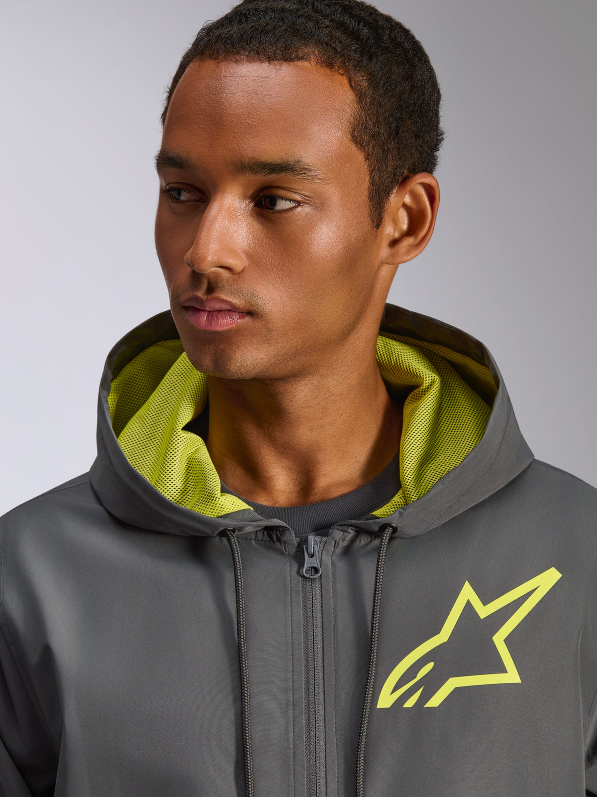Alpinestars Speeder Chromium Windbreaker-Jacke, Anthrazit mit leuchtgelben Akzenten, gelbes Stern-Logo auf der Brust und passendes Mesh-Kapuzenfutter, leichte Freizeit-Windjacke