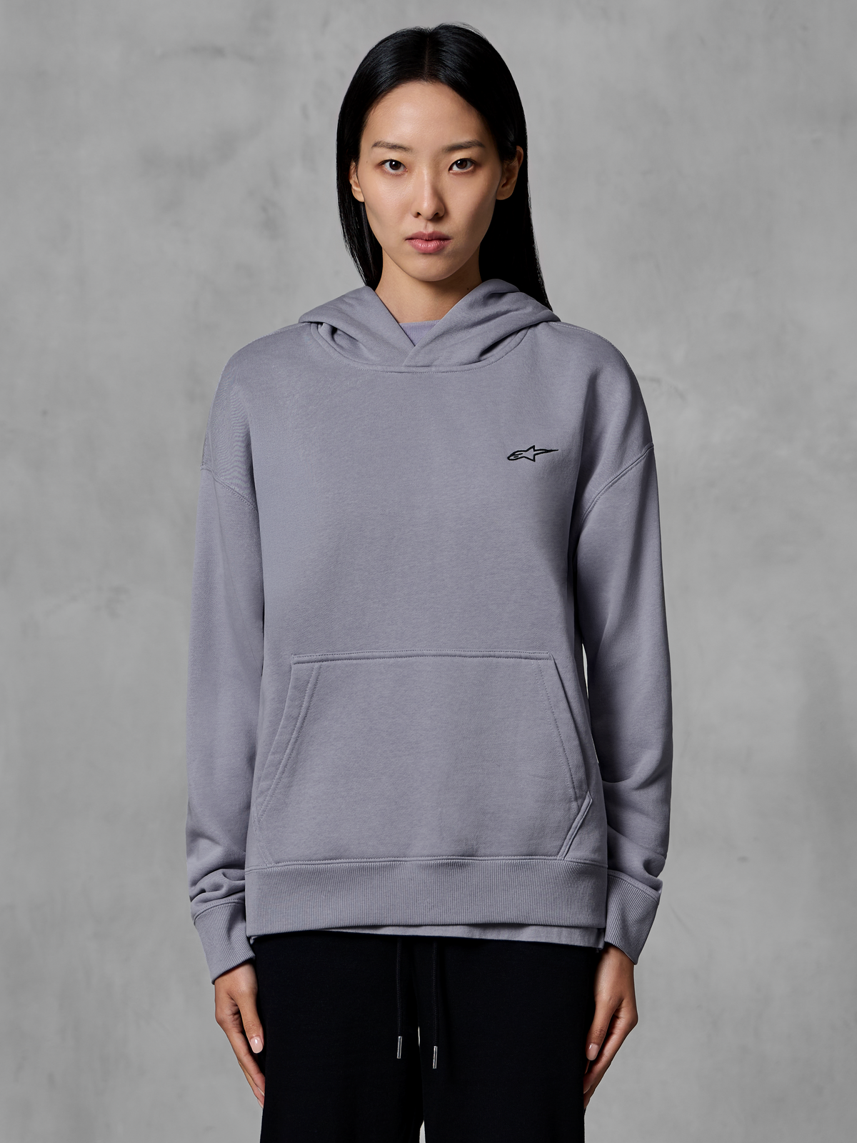 Alpinestars Essentials Ageless Hoodie, sportswear décontracté, argent avec petit logo noir, poche kangourou, sweat à capuche, porté par un mannequin, vêtement lifestyle moderne