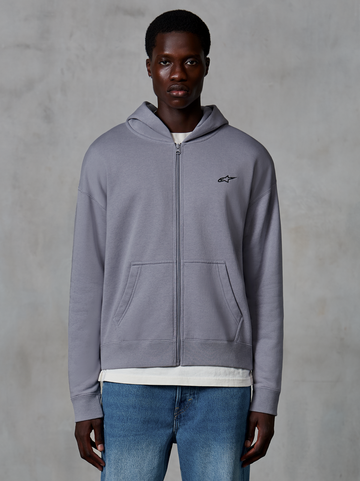 Sweat à capuche zippé Alpinestars Essentials Ageless, Argent, streetwear décontracté porté par un mannequin, polaire zippée avec petit logo Astars noir sur la poitrine, poches kangourou, coupe décontractée