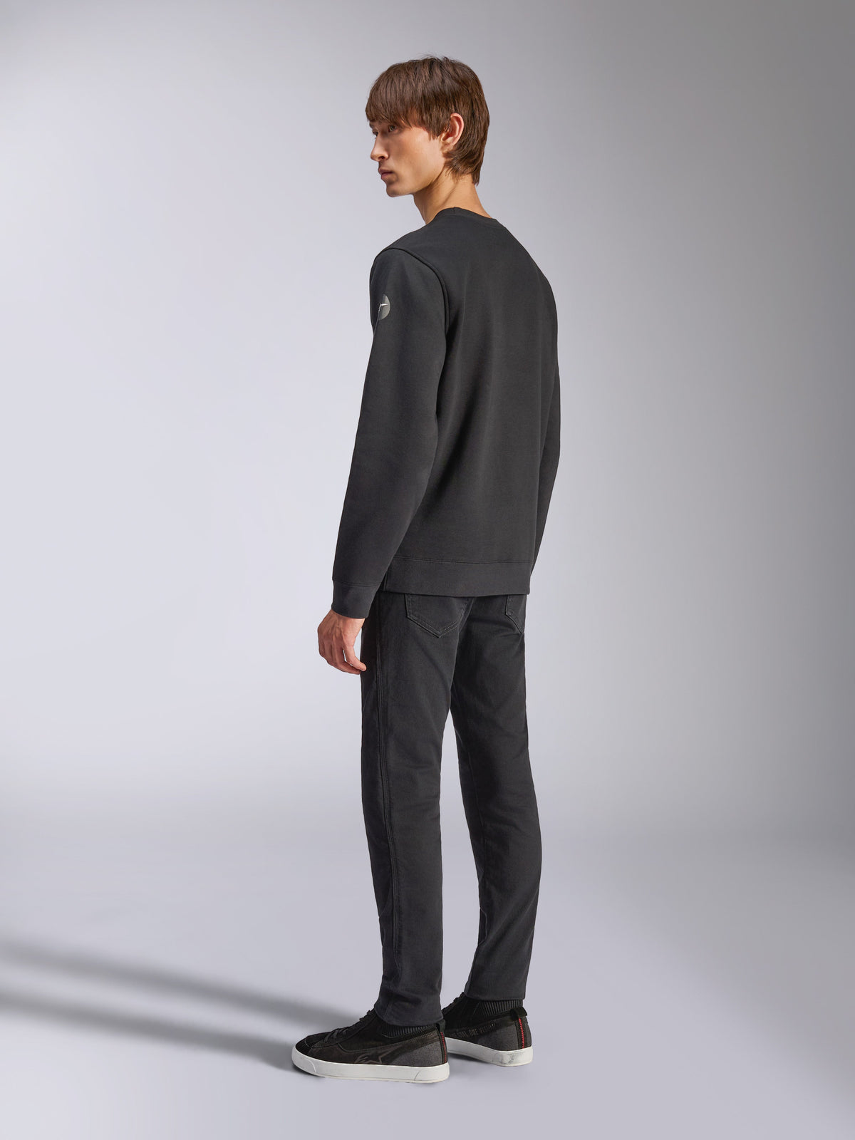 Alpinestars Bettern Crew, Fleece-Pullover, Schwarz, männliches Model in Rück- und Seitenansicht, mit gerippten Bündchen und Saum sowie einem kleinen Logo am Ärmel, lässige, vom Motorsport inspirierte Streetwear