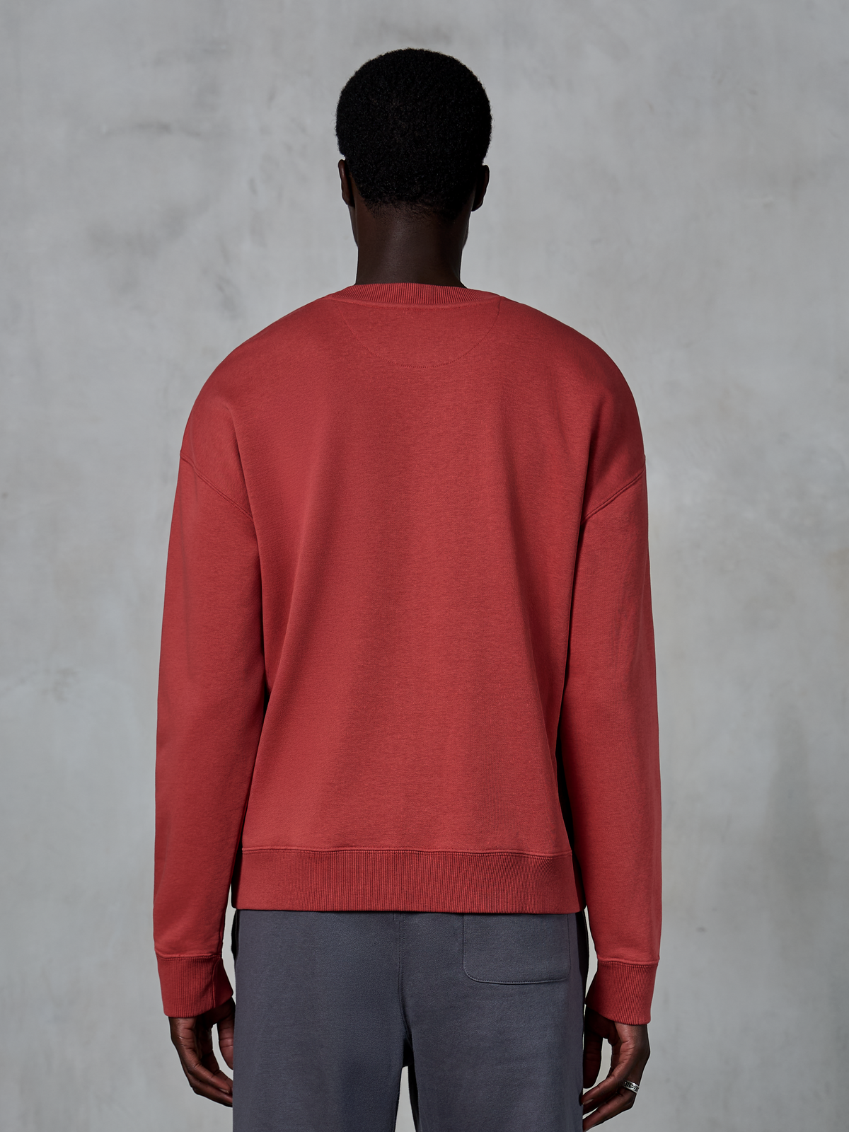 Alpinestars Essentials Ageless Crew, sweat-shirt à col rond rouge brique, vue de dos du mannequin portant un pull à coupe décontractée, col et poignets côtelés, streetwear décontracté inspiré du sport automobile