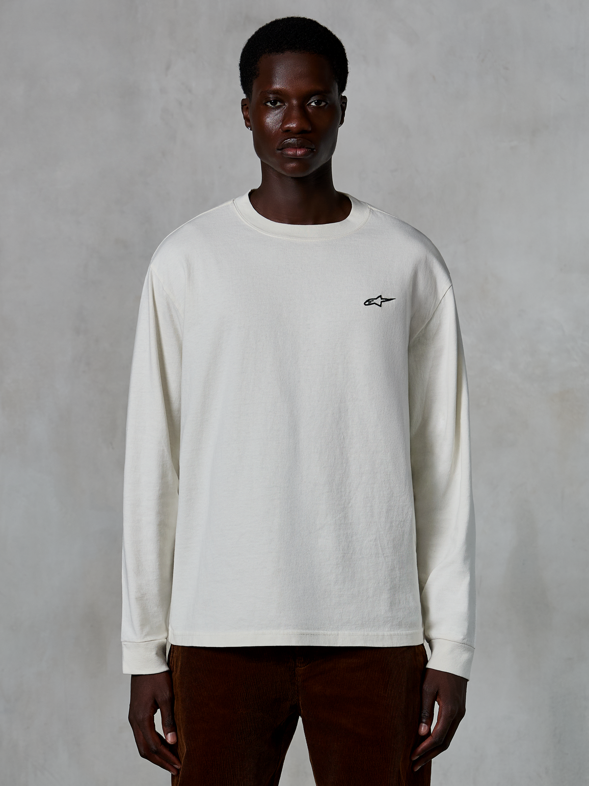 Alpinestars Essentials Ageless LS Tee, Langarmshirt, Off-White, kleines schwarzes Stern-Logo auf der Brust, lässige Streetwear, entspannte Passform, getragen von einem Modell