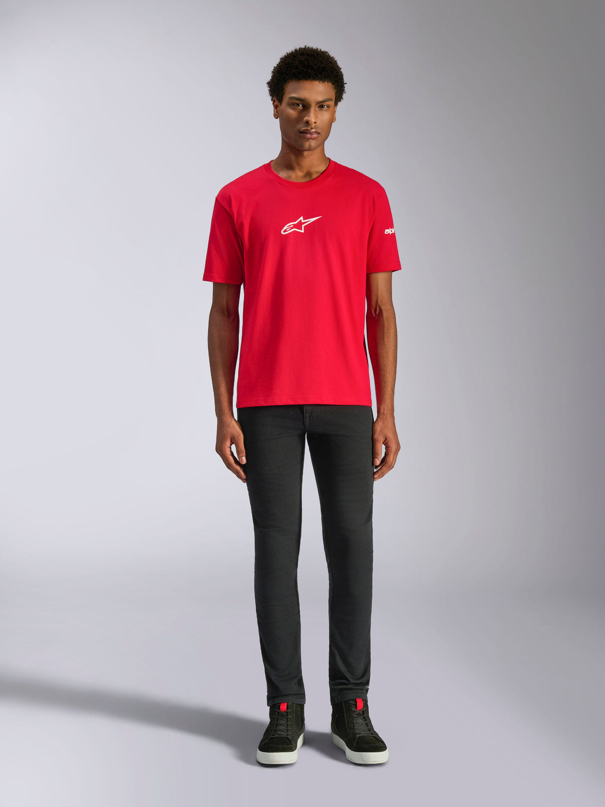 T-shirt Alpinestars Frontal CSF, t-shirt à manches courtes, rouge, petit logo Astars blanc sur la poitrine, porté par un mannequin avec un pantalon et des chaussures noirs, vêtement de sport de performance décontracté