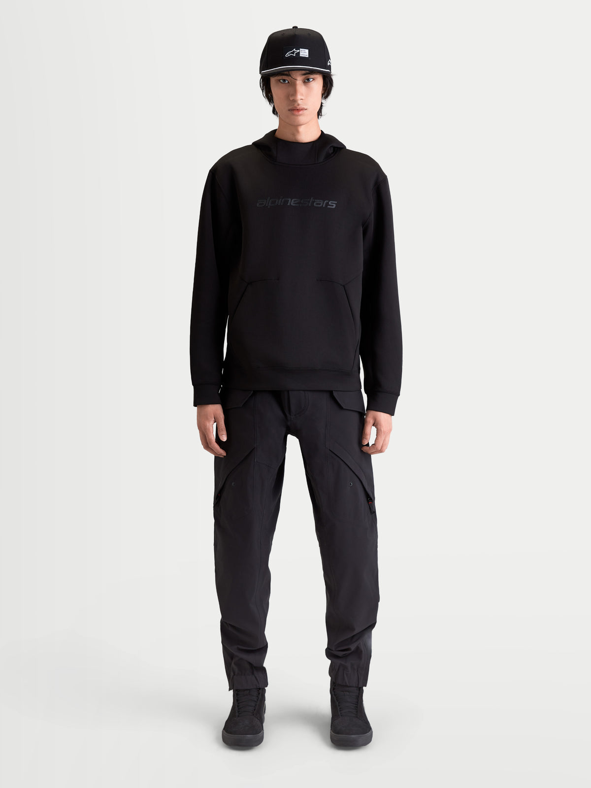 Alpinestars Sweat À Capuche Datrix, sweat à capuche sportswear pour homme, noir, avec marquage HD ton sur ton, polaire double face et poche avec détail de pli, porté par un modèle.