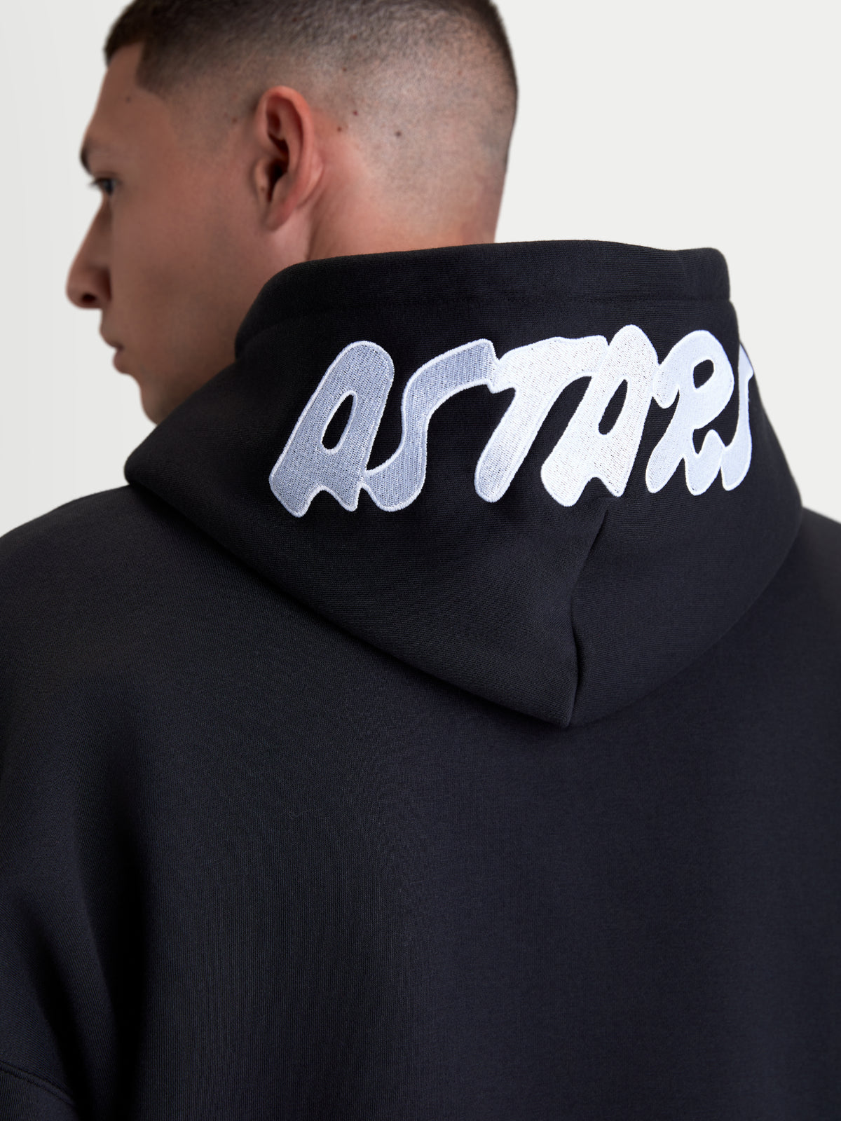 Alpinestars Sweat À Capuche Pioneer Oversize, sweat de sportswear en polaire, noir et blanc, vue de dos rapprochée avec logo ASTARS blanc brodé sur la capuche, construction en mélange de coton premium