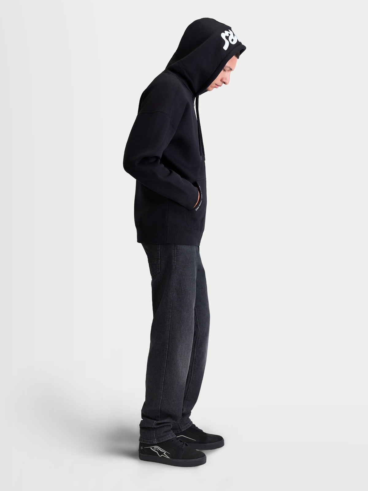 Alpinestars Sweat à capuche Pioneer Oversize, sweat à capuche zippé sportswear pour homme, noir avec détails brodés blancs, coupe oversize décontractée, fermeture éclair et poche kangourou, porté par un modèle avec la capuche relevée
