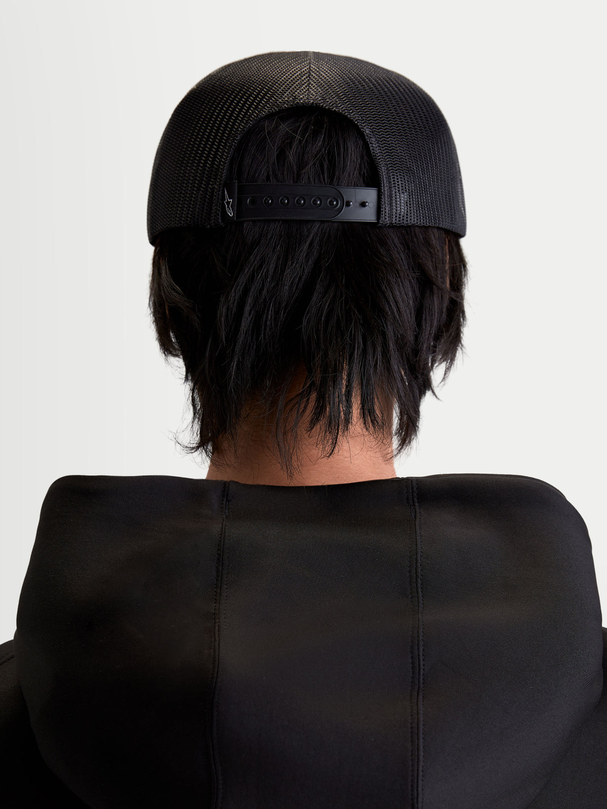 Alpinestars Casquette Trucker Gravel, casquette sportswear noire, vue de dos sur modèle montrant l'arrière en maille polyester respirante et la fermeture à pression réglable, style décontracté unisexe