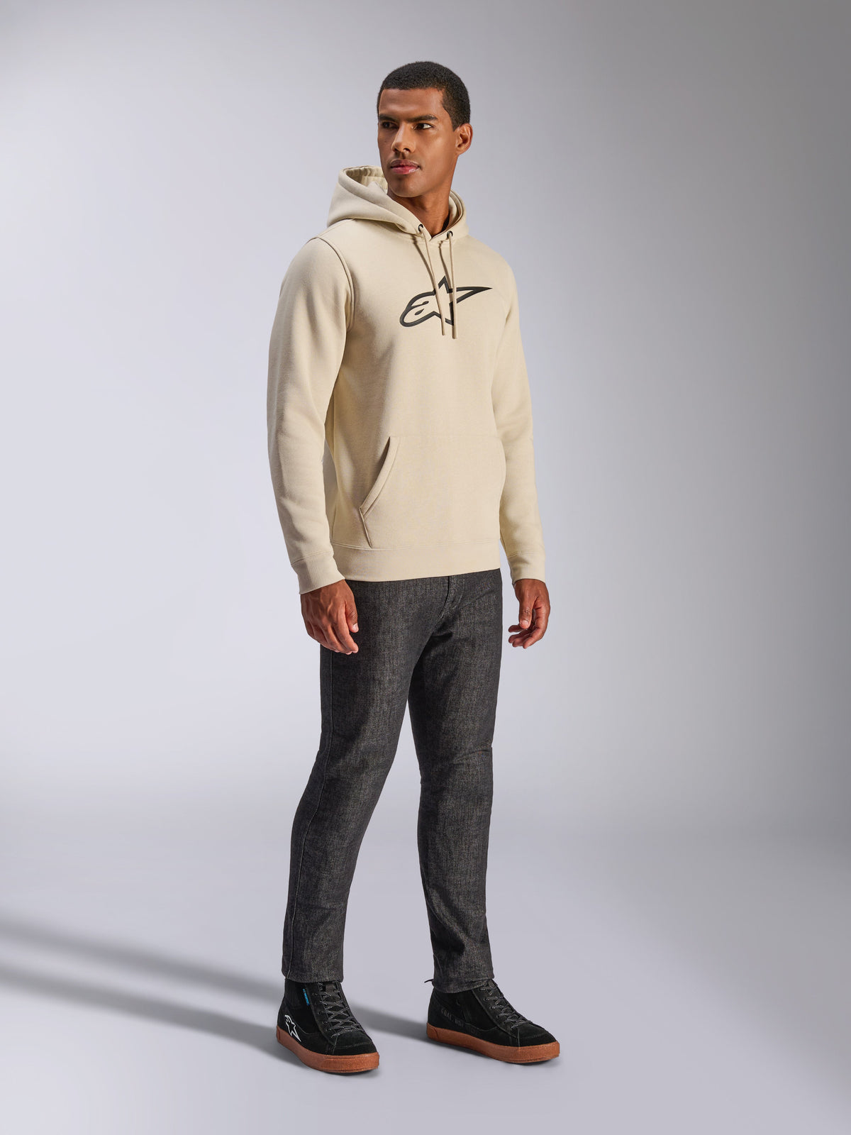 Alpinestars Ageless V3 Hoodie, casual streetwear, Off White with black embroidered logo, hooded pullover fleece, long sleeves, front pouch pocket, paired with dark jeans and black sneakers