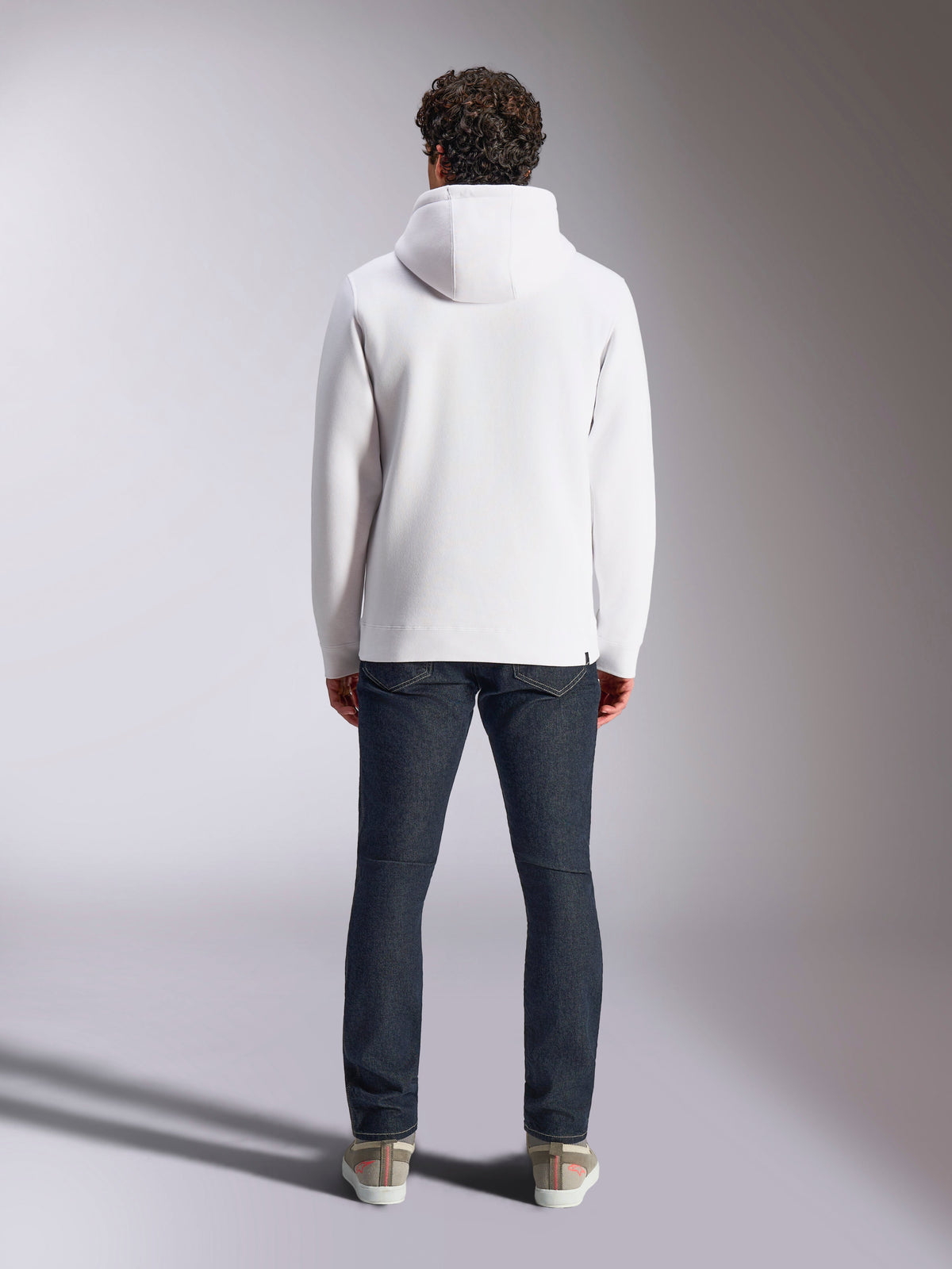 Sweat à capuche Alpinestars Blaze V3, hoodie blanc décontracté style sportswear, vue de dos du pull en polaire, design épuré avec poignets et ourlet côtelés, porté avec un jean bleu foncé et des baskets, vêtement lifestyle moderne inspiré du sport automobile