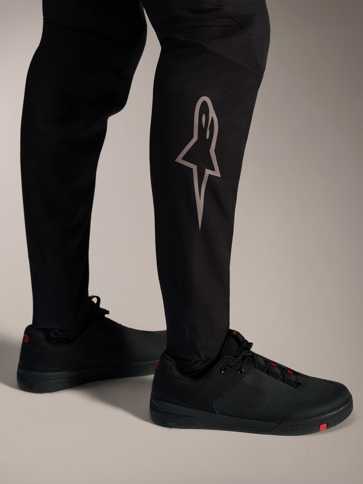 Zwarte A-Supra Elite MTB-broek met zilveren Astars-logo op het onderbeen voor high-performance mountainbiken.