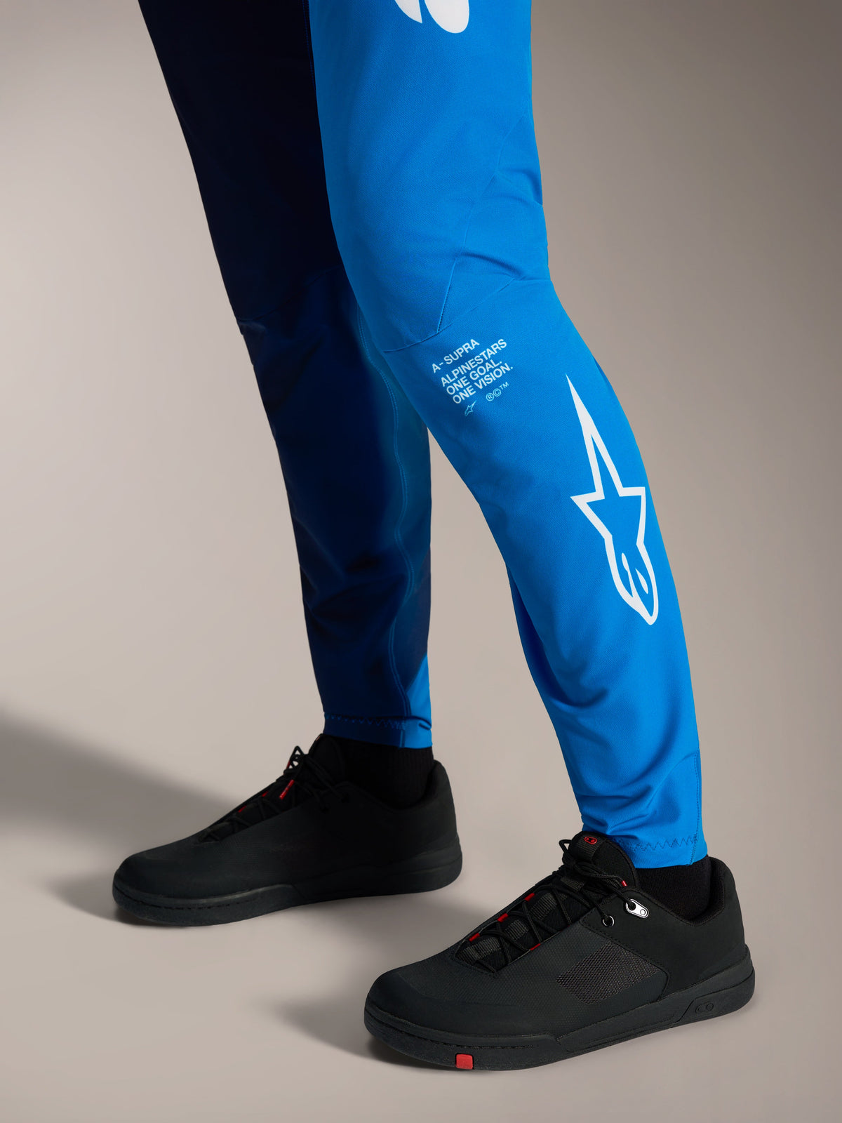 A-Supra Elite Hose in Faded Bright Blue mit weißem Astars-Logo am Unterschenkel und schwarzen MTB-Schuhen.