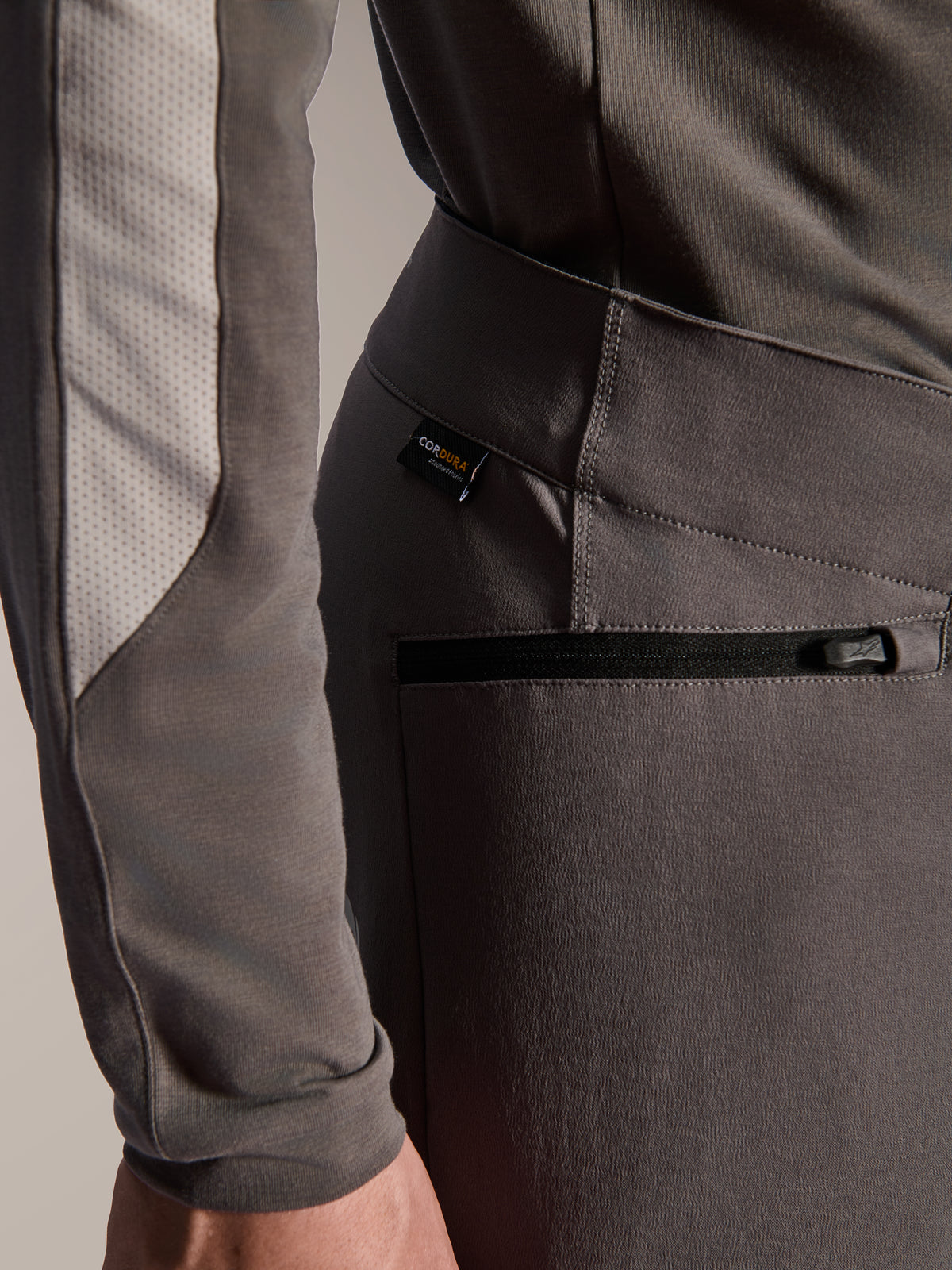 Alpinestars A-Dura Elite Pants, donkergrijze mountainbikebroek, close-up detail van zijzak met ritssluiting en Cordura-stoflabel, duurzaam 4-way stretch textiel voor off-road prestaties