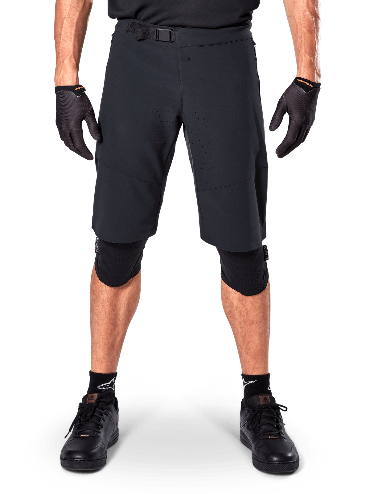 Alpinestars A-Aria Elite Shorts, mountainbike shorts, zwart, gedragen met kniebeschermers en zwarte handschoenen, voorzien van lasergesneden ventilatie en een verstelbare gesp in de taille, prestatiegerichte off-road fietskleding