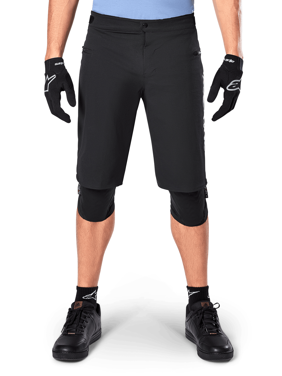Alpinestars A-Dura Elite Shorts, Black Mountain Bike Shorts, worn by a rider with black gloves and knee pads, featuring front snap closure and zippered pockets, durable Cordura material for off-road cycling