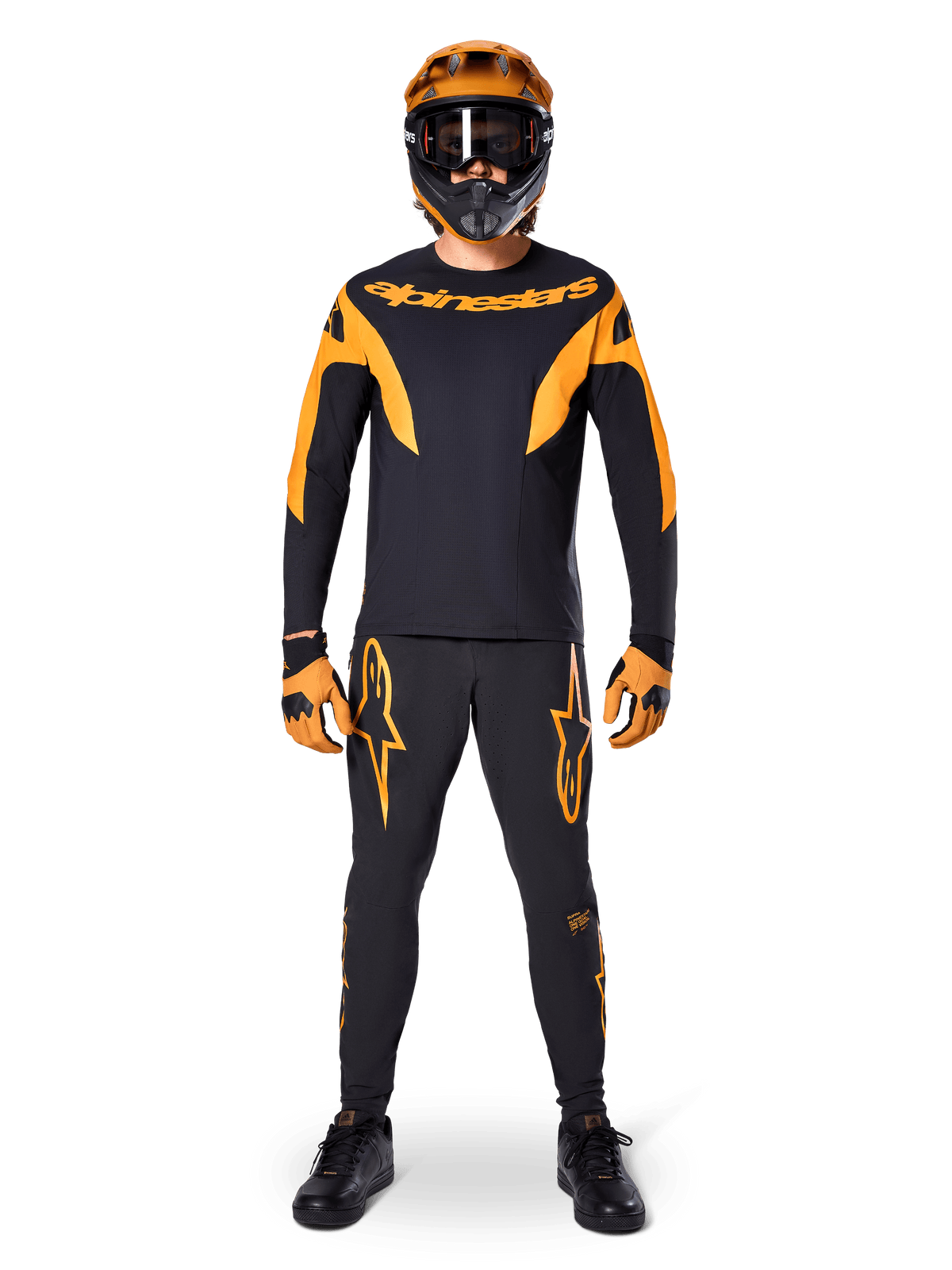 Alpinestars A-Supra Race Pants, MTB Racing Pants, Black and Orange, worn by a rider in a complete racing kit including a black and orange jersey, orange helmet, and matching gloves, featuring bold orange star logos on the legs
