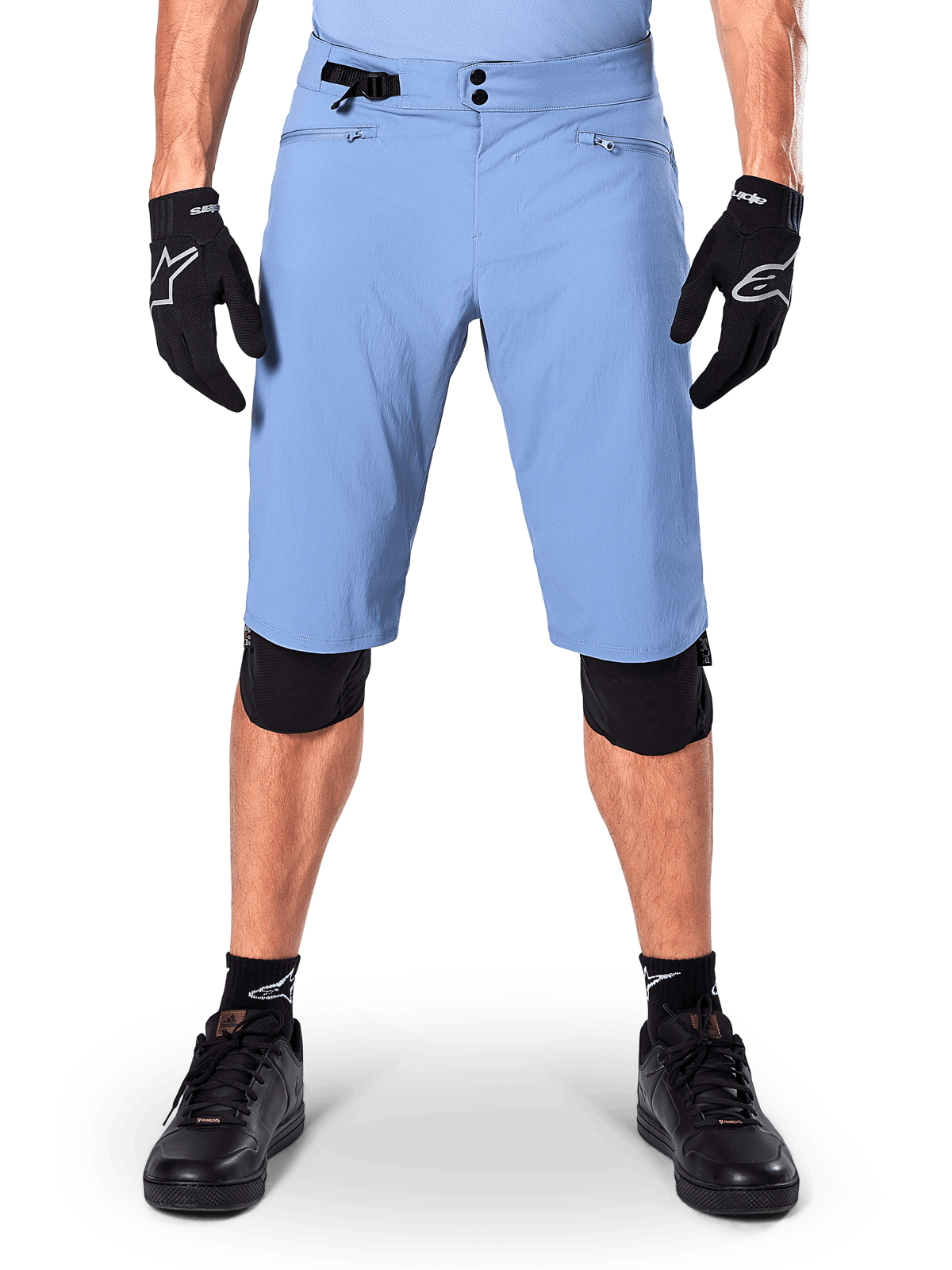 Short Alpinestars A-Dura, short de VTT bleu Infinity Blue, porté avec des gants noirs et des genouillères, doté d'une double fermeture à pression et d'un ajusteur de taille latéral, équipement de cyclisme haute performance pour le VTT