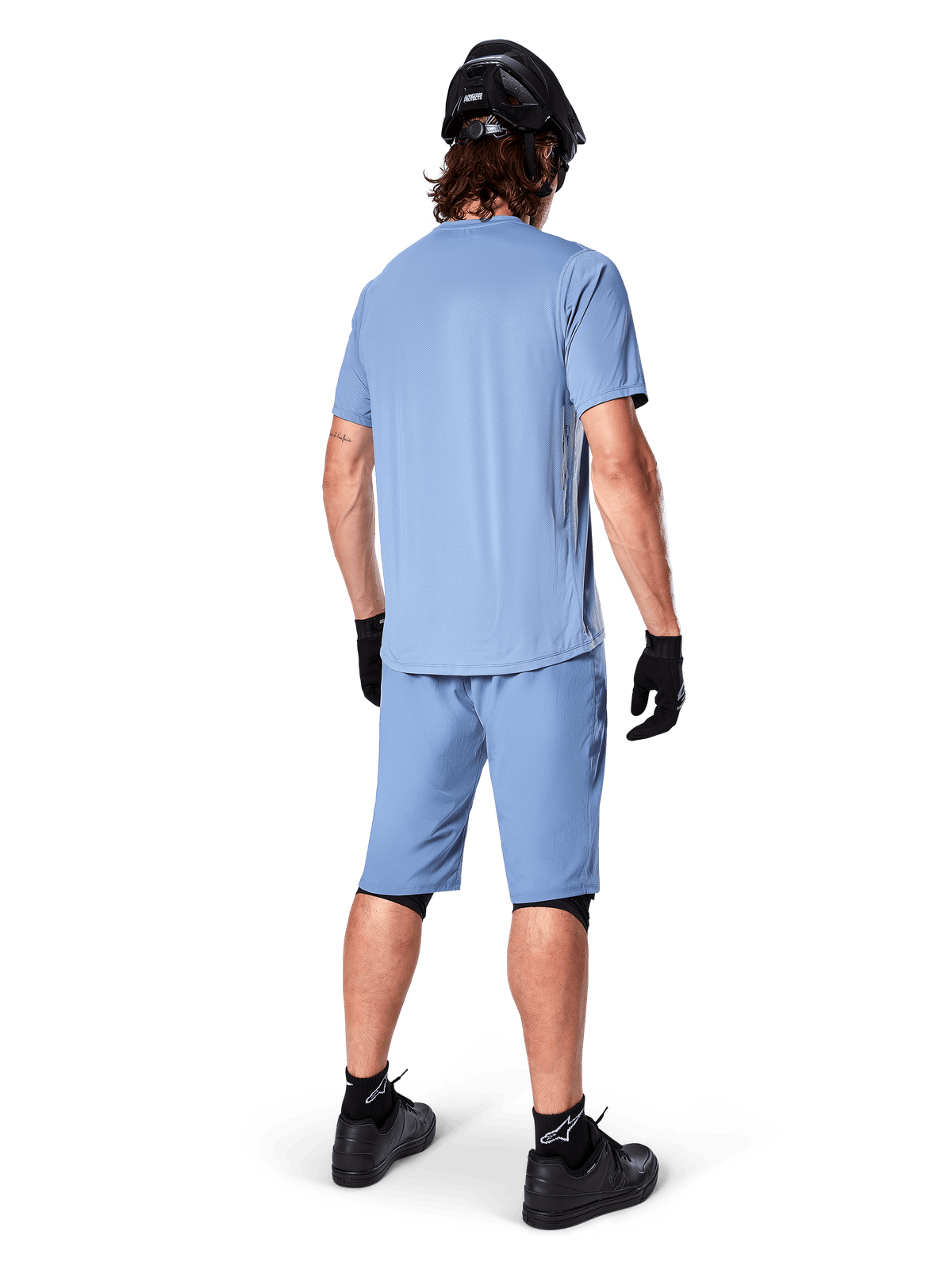 Vue arrière d'un vététiste portant le short Alpinestars A-Dura en Infinity Blue, maillot à manches courtes assorti, casque noir, gants noirs et chaussures noires, équipement de performance coordonné pour le trail VTT