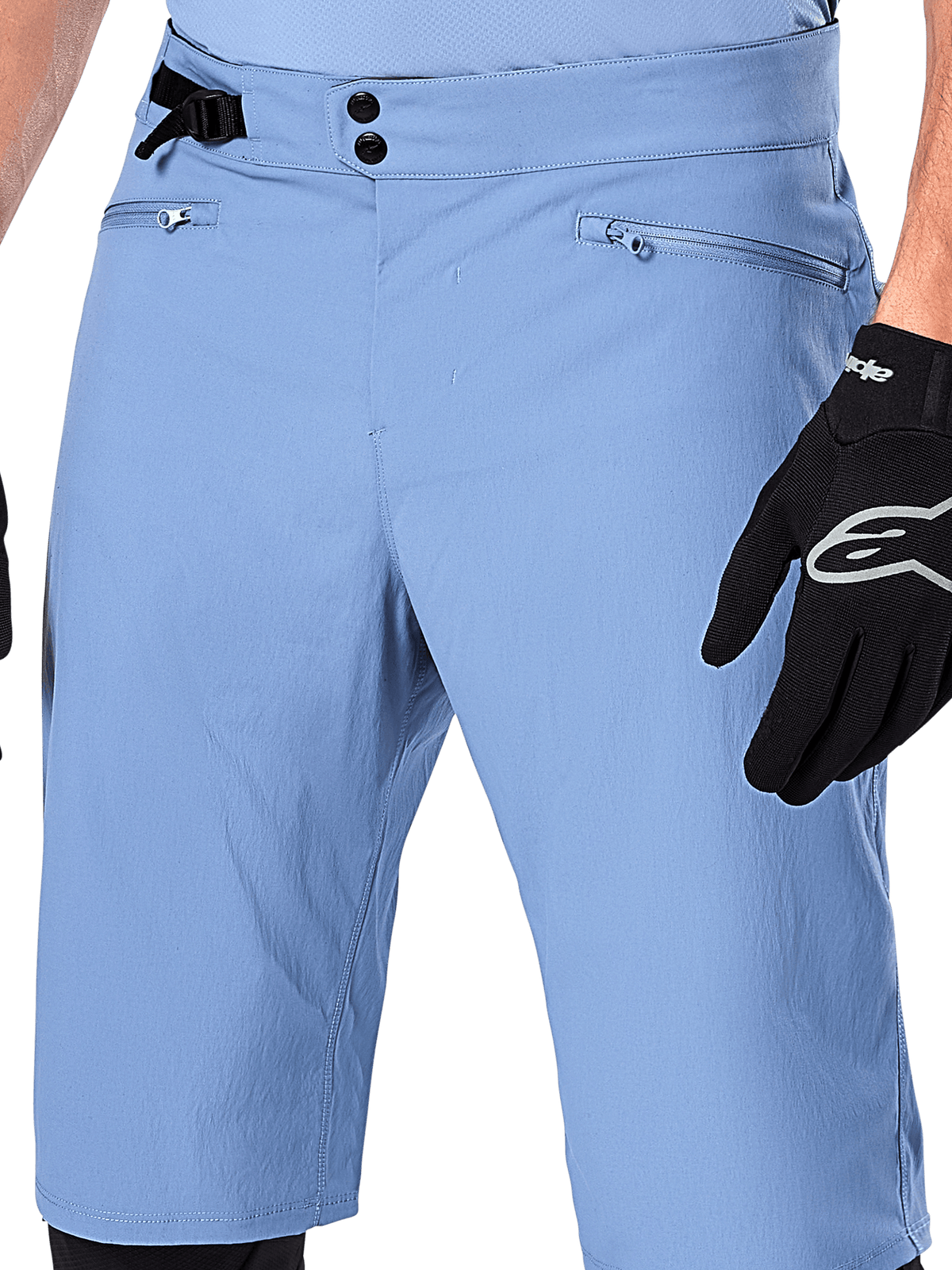 Short Alpinestars A-Dura, short de VTT bleu Infinity, gros plan sur la taille doté d'une double fermeture à pression, d'un ajusteur latéral et de poches zippées doublées en maille, porté avec un gant Alpinestars noir