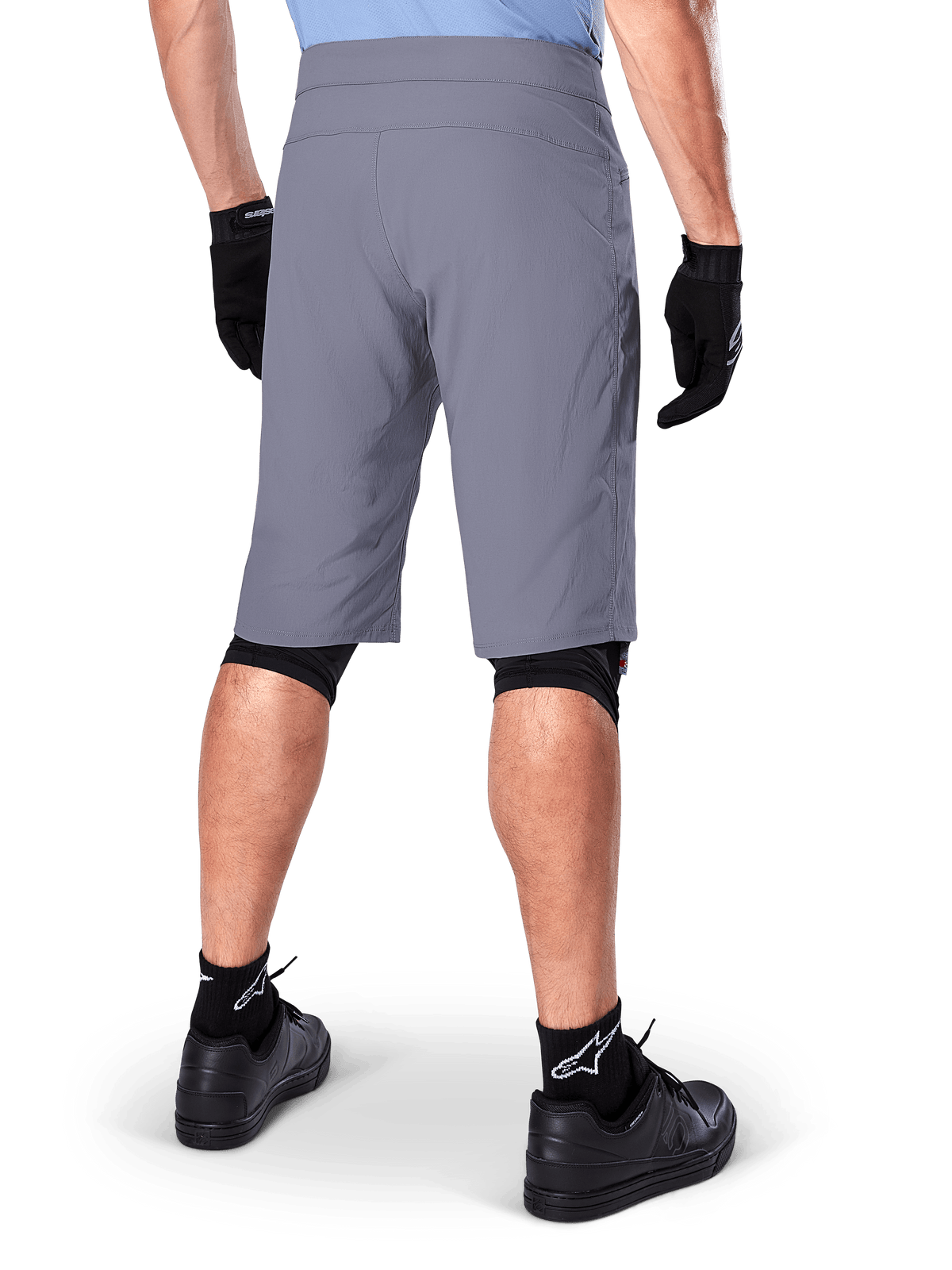 Alpinestars A-Dura Shorts, donkergrijze mountainbikeshorts, achteraanzicht getoond op een rijder, gedragen met zwarte handschoenen, zwarte knie-liners en zwarte Alpinestars-logosokken, duurzame constructie voor off-road fietsen