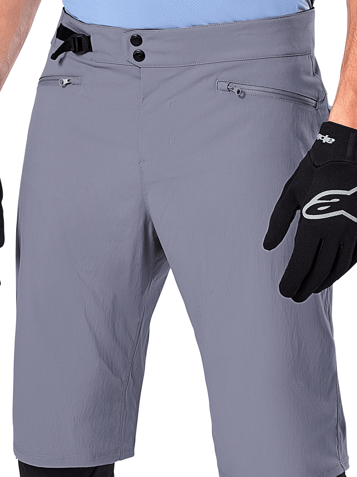 Alpinestars A-Dura Shorts, MTB-shorts, donkergrijs, close-up van de taille met dubbele drukknoopsluiting, zijdelingse tailleversteller en ritszakken, gecombineerd met zwarte fietshandschoenen, duurzame mountainbikekleding.