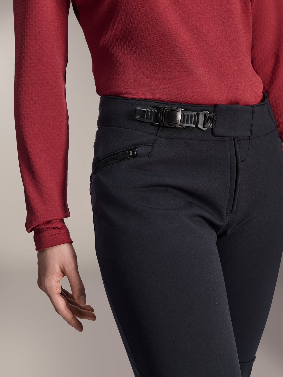 Alpinestars Stella A-Dura Thermal broek, MTB-broek voor dames, zwart, detailopname van het ratelsluitsysteem op de tailleband en zijzak met rits, gedragen met een donkerrode top met lange mouwen, duurzame uitrusting voor ritten op de trail in koud weer
